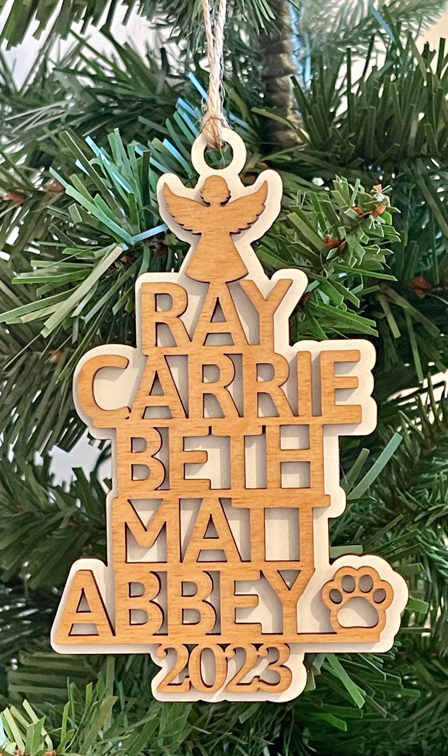The birch wood version of the customized ornament is shown with a green Christmas tree backdrop.